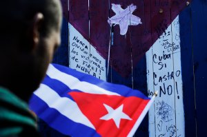 A man holds a Cuban flag as people gather to celebrate the death of longtime Cuban leader Fidel Castro on November 26, 2016 in Union City, New Jersey. (Credit: Euardo Munoz Alvarez/AFP/Getty Images)