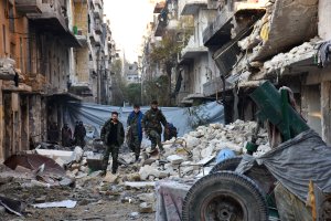 Syrian pro-government forces walk amidst heavy destruction in Aleppo's Bustan al-Basha neighbourhood on Nov. 28, 2016, during their assault to retake the entire northern city from rebel fighters. (Credit: George Ourfalian/AFP/Getty Images)