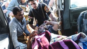 Iraqi soldiers load an injured man into a van on Nov. 4, 2016, near the village of Gogjali, on the eastern edge of Mosul, as families flee the violence due to the ongoing operation by Iraqi forces to retake the city from Islamic State group jihadists. (Credit: Bulent Kilic/AFP/Getty Images)