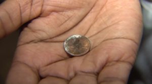 Samantha Knox holds the penny that was lodged in her son's esophagus on Nov. 17, 2016. (Credit: KTLA)
