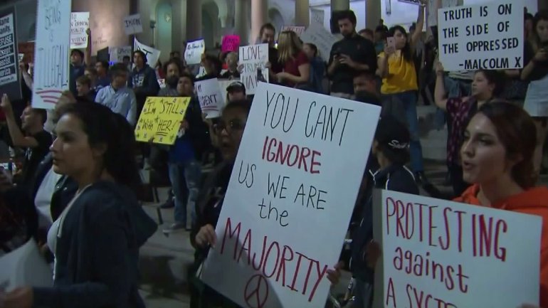 Protesters hold signs on the steps of L.A. City Hall on Nov. 10, 2016. (Credit: KTLA)