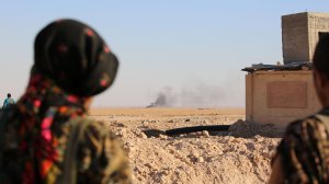 Members of U.S.-backed Kurdish-Arab forces look at smoke billowing due to the fighting as they hold a position on the frontline 30 miles north of Raqa, on Nov. 6, 2016. (Credit: Delil Souleiman/AFP/Getty Images)