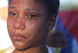 A young woman cries after watching the military jeep towing a trailer with the flag-draped chest containing the remains of former President of Cuba Fidel Castro drive past to his burial at the Cementerio Santa Ifigenia on Dec. 4, 2016 in Santiago de Cuba. (Credit: Joe Raedle / Getty Images)