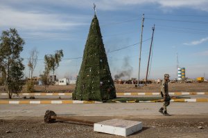 An NPU fighter walks in front of a large Christmas tree erected on the main road on Dec. 22, 2016 in Mosul, Iraq. (Credit: Chris McGrath / Getty Images)