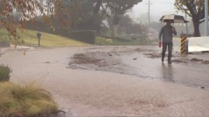 A man walks along a rainy street with mudflows in an undated file photo. (Credit: KTLA)
