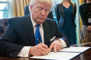 President Donald Trump signs an executive order in the Oval Office at the White House in Washington, DC, on January 24, 2017. (Credit: NICHOLAS KAMM/AFP/Getty Images)