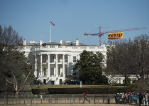 Greenpeace protesters unfold a banner reading "Resist" from atop a construction crane behind the White House Jan. 25, 2017, in Washington, D.C. The banner, flying high enough to be seen from the White House, is in opposition to the policies of President Donald Trump. (Credit: SAUL LOEB/AFP/Getty Images)