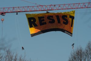 Greenpeace protesters hang from a banner reading "Resist" from atop a construction crane behind the White House Jan. 25, 2017, in Washington, D.C. (Credit: NICHOLAS KAMM/AFP/Getty Images)