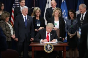 U.S. President Donald Trump signs two executive orders during a visit to the Department of Homeland Security with Vice President Mike Pence, Homeland Security Secretary John Kelly (R) and other officials Jan. 25, 2017, in Washington, D.C. (Credit: Chip Somodevilla/Getty Images)