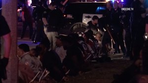 Individuals are detained on a curb after the party bus they were on was pulled over in Huntington Beach on Jan. 7, 2016. (Credit: OnScene)