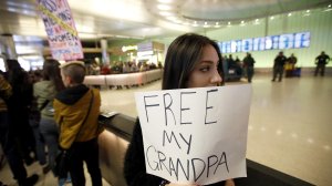 Kamryn Taghizadeh, 18, holds up a sign as she waits for her grandfather Reza Taghizadeh, 78, a minimalist painter who she says was detained as he arrived to Tom Bradley International Terminal from Iran on Jan. 28, 2017. (Credit: Francine Orr)