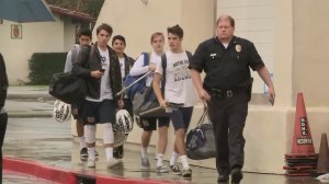 A Los Angeles Police officer escorts students out of Notre Dame High School after a bomb threat was sent to the campus via email. (Credit: KTLA)