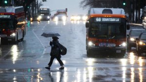 A pedestrian scurries across the street under her umbrella in downtown Los Angeles Friday morning. (Credit: Irfan Khan/Los Angeles Times)