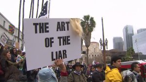 A protester holds a sign on the steps of Los Angeles City Hall for "Not My Presidents Day" on Feb. 20, 2017. (Credit: KTLA)