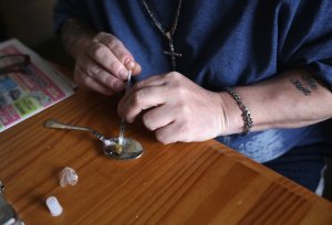 A heroin user prepares to inject himself on March 23, 2016, in New London, Connecticut. (Credit: John Moore / Getty Images)