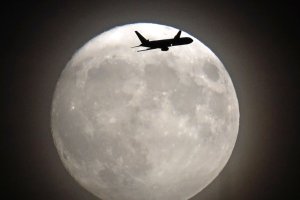 A commercial jet flies in front of the moon on its approach to Heathrow airport in west London on November 13, 2016. (Credit: ADRIAN DENNIS/AFP/Getty Images) 