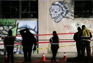 Workers and emergency responders look at a warehouse in which a fire claimed the lives of at least 36 people on Dec. 5, 2016, in Oakland. (Credit: Elijah Nouvelage / Getty Images)