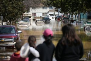 People look at cars and homes engulfed in floodwaters on Feb. 22, 2017, in San Jose. (Credit: Elijah Nouvelage / Getty Images)