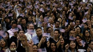 Newly sworn-in Americans wave flags after taking the oath of citizenship. (Credit: Luis Sinco / Los Angeles Times) 