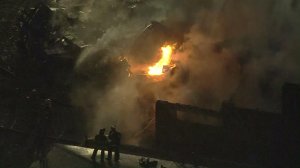 Flames continue to rise from a Riverside home after a plane crashed into it Feb. 27, 2017. (Credit: KTLA)