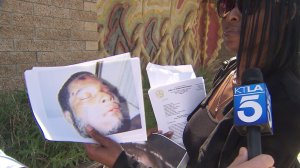 Nefertiti Brown holds up a picture of her son, who she says was beat to death while in police custody. (Credit: KTLA)