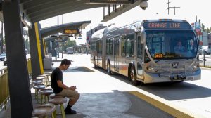 A Metro rider waits for an Orange Line bus at the North Hollywood station. That busway will be the first route to run only electric buses. (Irfan Khan / Los Angeles Times)