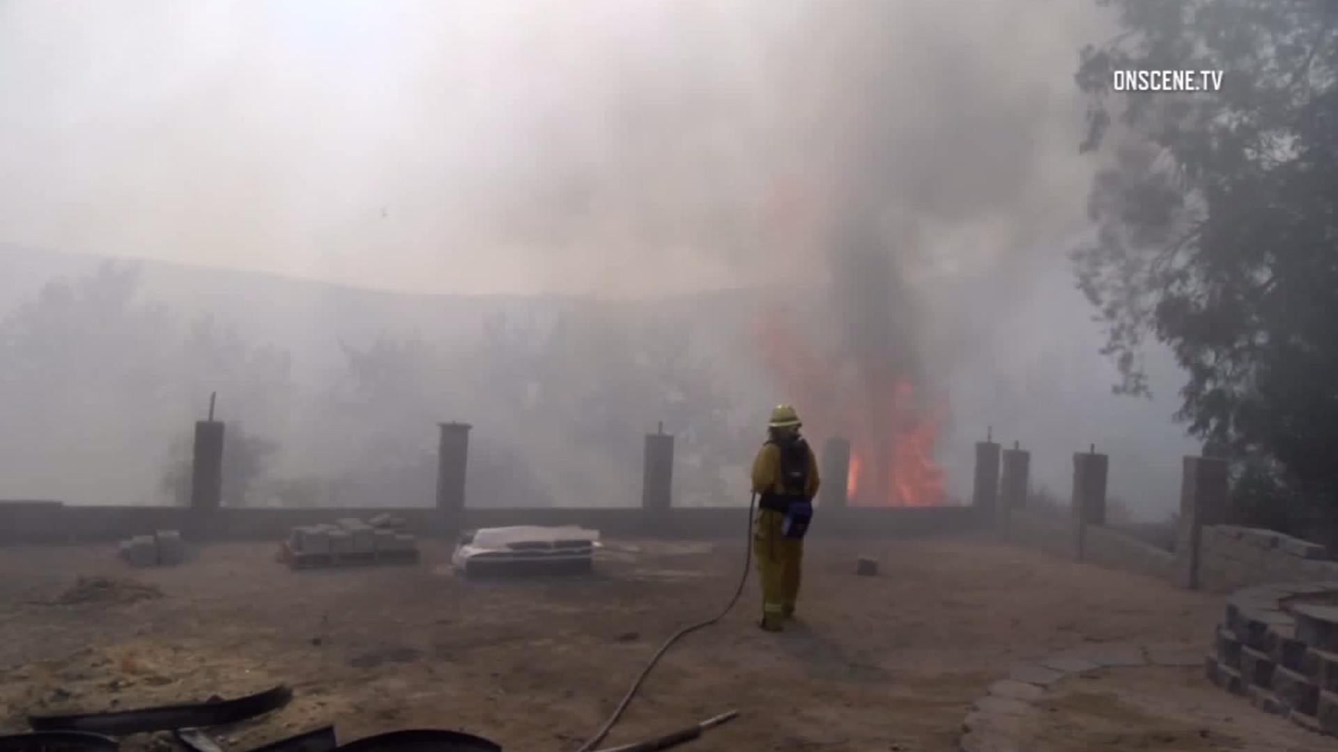 A firefighter works to put out flames near homes during the Seine Fire in Highland on July 22, 2017. (Credit: OnScene.TV)
