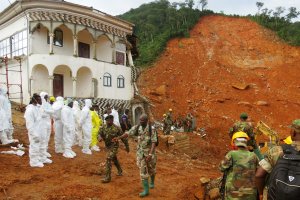 Search and rescue team members and soldiers operate near a mudslide site and damaged building near Freetown on August 15, 2017, after landslides struck the capital of the west African state of Sierra Leone. (Credit: SAIDU BAH/AFP/Getty Images)