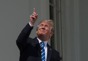 US President Donald Trump looks up at the partial solar eclipse from the balcony of the White House in Washington, DC, on August 21, 2017. (Credit: NICHOLAS KAMM/AFP/Getty Images)