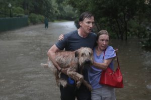 Andrew White, left, helps a neighbor down a street after rescuing her from her home in his boat in Houston after it was inundated with flooding from Hurricane Harvey on Aug. 27, 2017. (Credit: Scott Olson / Getty Images)