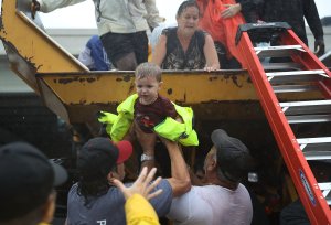 A child is helped off the back of a rescue truck after his family evacuated their home after it was inundated with flooding following Hurricane Harvey on Aug. 28, 2017, in Houston, Texas. (Credit: Joe Raedle / Getty Images)