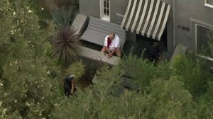 The man shot during a robbery in Mid-Wilshire can be seen sitting on a porch, bleeding. (Credit: KTLA)