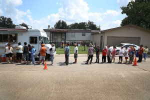 People line up to receive food and water from a Salvation Army truck after their homes were inundated with flood waters during Hurricane and Tropical Storm Harvey on Sept. 2, 2017 in Houston, Texas. (Credit: Joe Raedle/Getty Images)