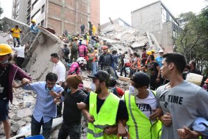 Rescuers, firefighters, policemen, soldiers and volunteers remove rubble and debris from a flattened building in search of survivors after a powerful quake in Mexico City on Sept. 19, 2017. (Credit: Ronaldo Schemidt / AFP / Getty Images)