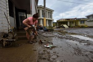 A woman removes mud from her damaged house in Toa Baja, 35 km from San Juan, Puerto Rico, on Sept. 23, 2017, where Rio Plata flooded during and after the passage of Hurricane Maria. (Credit: Hector Retamal / AFP / Getty Images)