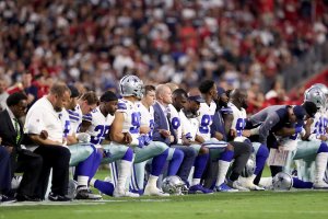 Members of the Dallas Cowboys link arms and kneel during the National Anthem before the start of the NFL game against the Arizona Cardinals at the University of Phoenix Stadium on September 25, 2017 (Credit: Christian Petersen/Getty Images)