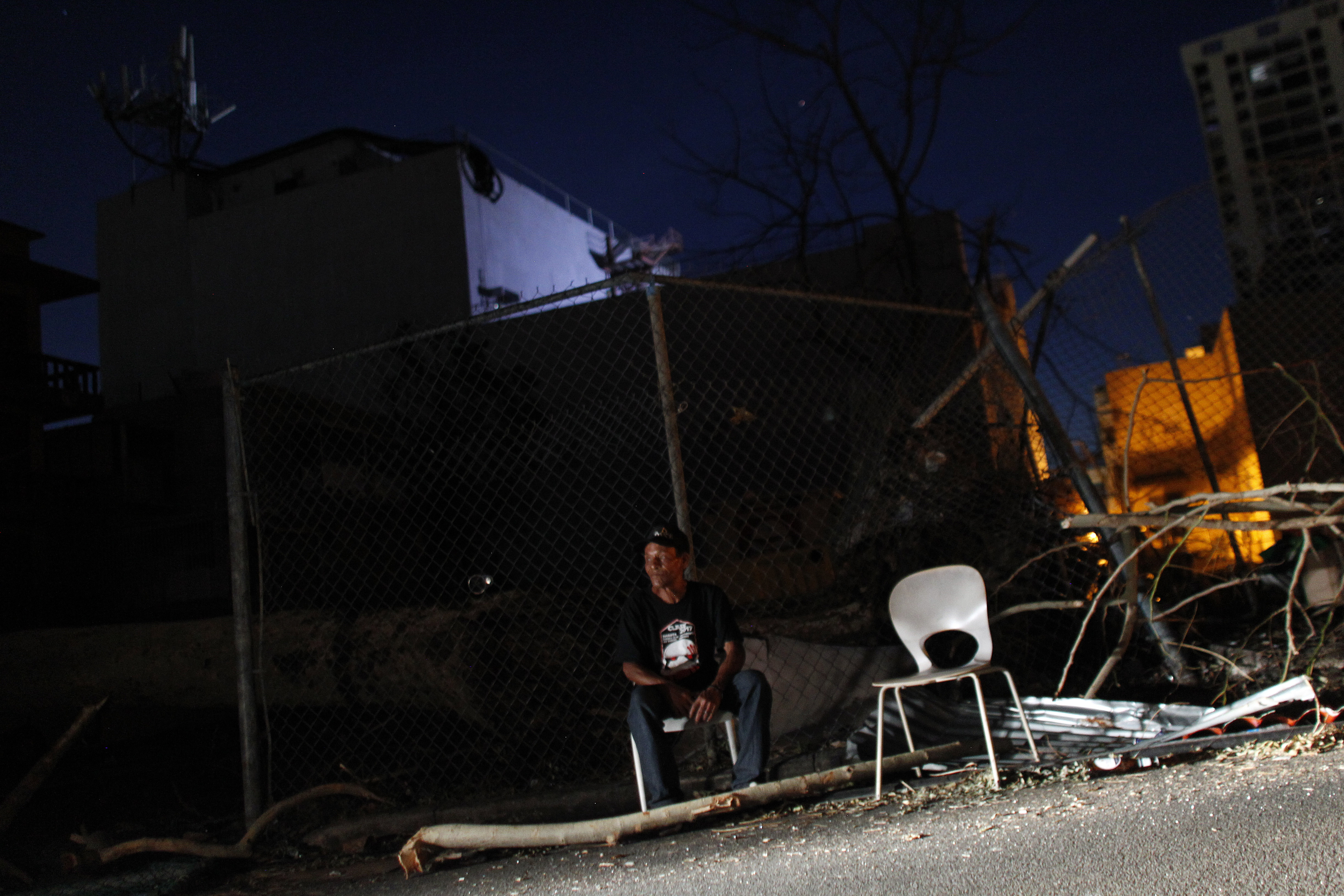 A man sits on a chair beside a road at night Sept. 25, 2017, in San Juan, Puerto Rico, where a 7 p.m. to 6 a.m. curfew has been imposed following the impact of Hurricane Maria on the island. (Credit: RICARDO ARDUENGO/AFP/Getty Images)