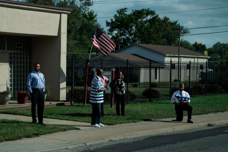A man takes a knee while holding an American flag as a motorcade with President Donald Trump drives to Indianapolis International Airport September 27, 2017 in Indianapolis. (Credit: BRENDAN SMIALOWSKI/AFP/Getty Images)