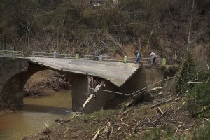 People cross a bridge what was destroyed when Hurricane Maria passed through on Sept. 27, 2017, in Corozal, Puerto Rico. (Credit: Joe Raedle / Getty Images)