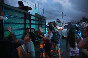 Hurricane survivors receive food and water being given out by volunteers and municipal police as they deal with the aftermath of Hurricane Maria on Sept. 28, 2017, in Toa Baja, Puerto Rico. (Credit: Joe Raedle / Getty Images)