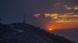 A couple survey the damage as they walk near a cross that remains standing amid the scorched hillside that destroyed three homes and a shed. (Allen J. Schaben / Los Angeles Times)