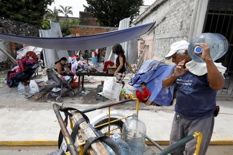 Margarita Martinez, left, shown with her children, sits where her home used to stand in the Mexican town of Jojutla, Morelos. (Credit: Gary Coronado / Los Angeles Times)