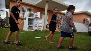 Children walk alongside hurricane-damaged furniture, in Vega Baja, Puerto Rico, on Sept. 30, 2017. (Credit: Hector Retamal/AFP/Getty Images)