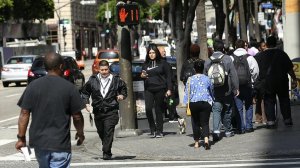 A pedestrian steps into the crosswalk as the signal above shows a red hand blinking at Hope and 7th streets in downtown Los Angeles in this undated photo. (Credit: Mel Melcon/Los Angeles Times)