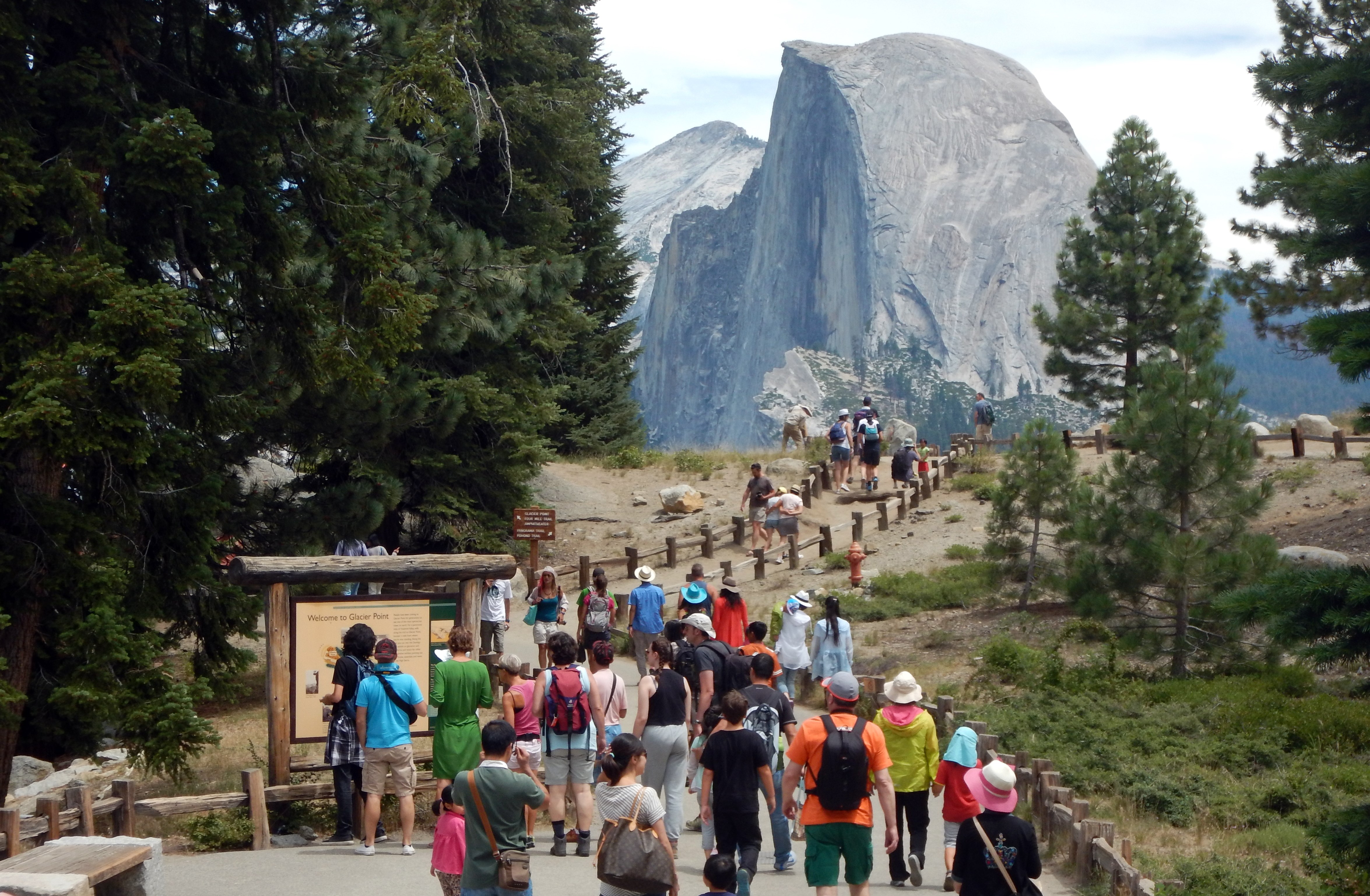 This Aug. 5, 2015, photo shows tourists walking out to Glacier Point with a background view of Half Dome at Yosemite National Park. (Credit: FREDERIC J. BROWN/AFP/Getty Images)