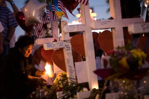 A woman lights candles at several of the 58 white crosses at a makeshift memorial on the south end of the Las Vegas Strip, Oct. 6, 2017 in Las Vegas, Nevada. (Credit: Drew Angerer / Getty Images)