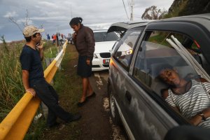 Family members gather while attempting to speak by phone with another family member along a roadside near the top of a mountain in Orocovis, more than two weeks after Hurricane Maria swept through Puerto Rico, on Oct. 6, 2017. (Credit: Mario Tama / Getty Images)