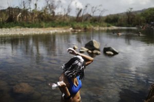 A woman washes her hair in the Espiritu Santo river, along hurricane-damaged forest, more than two weeks after Hurricane Maria hit the island, on Oct. 8, 2017, in Palmer, Puerto Rico. (Credit: Mario Tama / Getty Images)