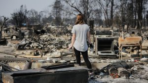 Margaret Curzon looks at the remains of her childhood home in Santa Rosa on Oct. 15, 2017, while holding the items of emotional importance she was able to salvage. (Credit: Elijah Nouvelage/Getty Images)