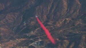 A DC-10 drops Phos-Chek at the edge of the Wildomar Fire on Oct. 26, 2017. (Credit: KTLA)